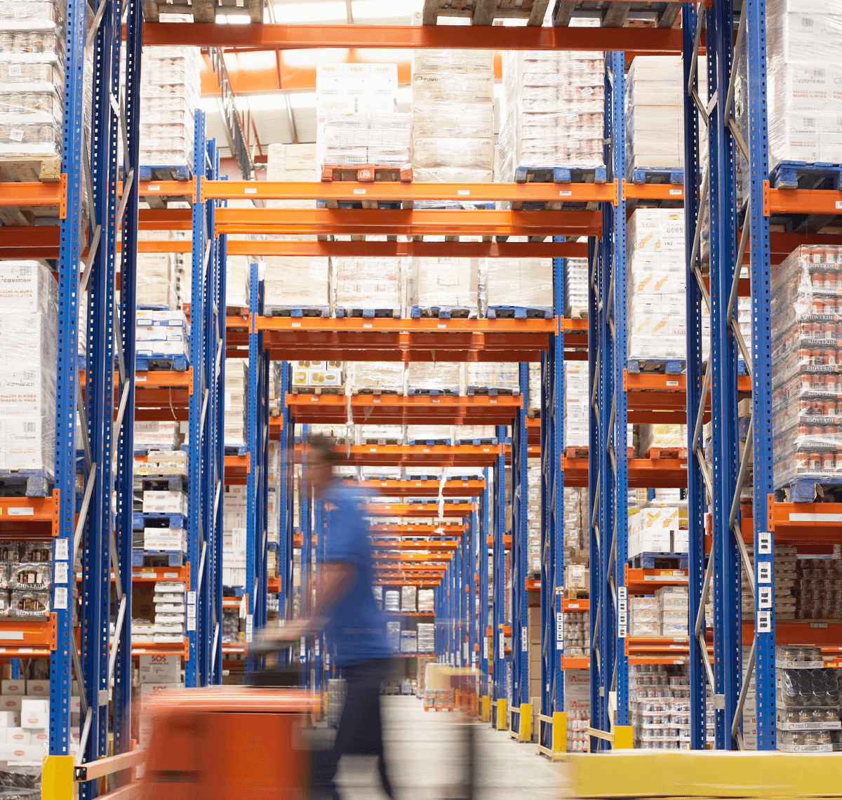 Man driving pallet jack through warehouse.